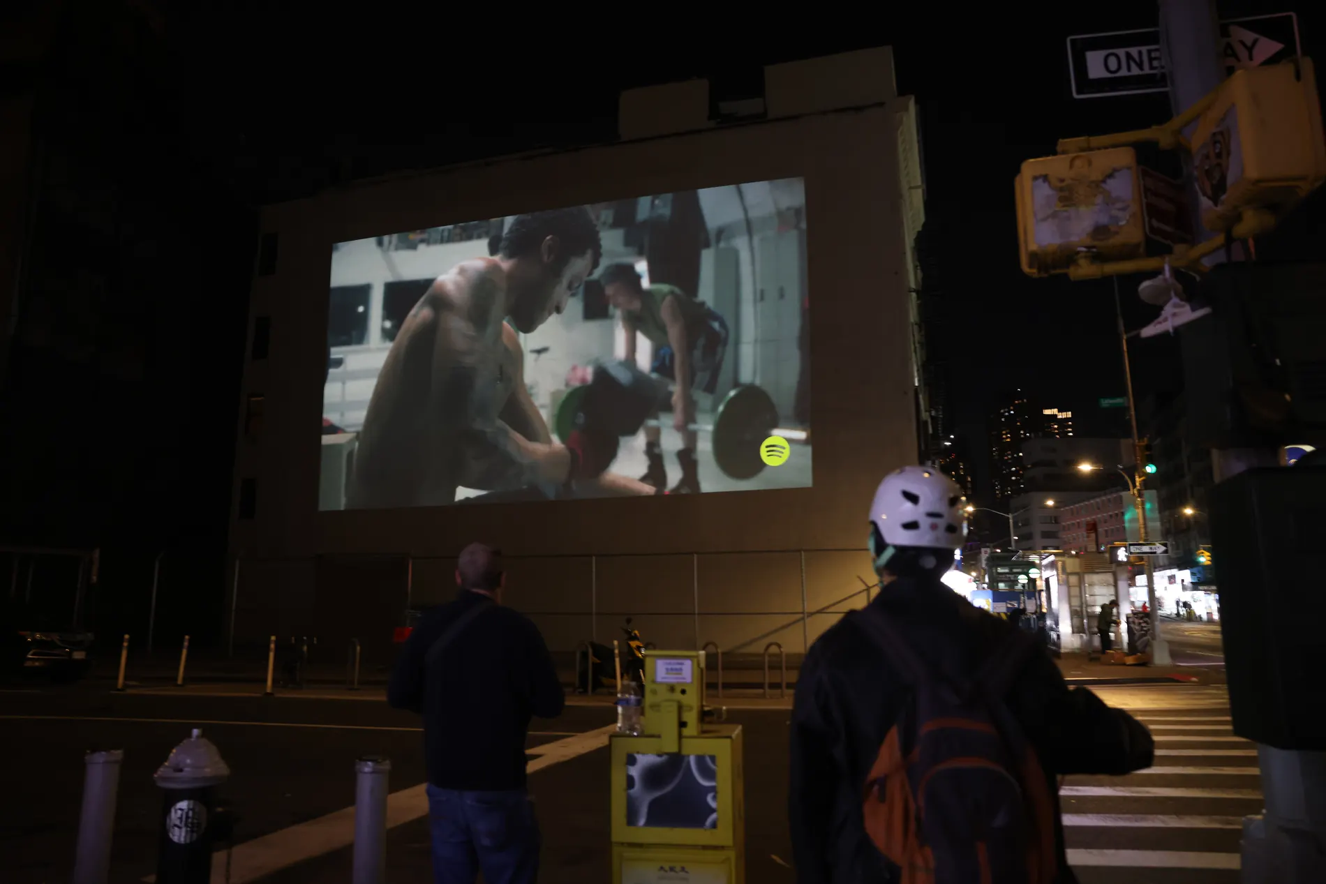 Sidewalk crowd watching a projected campaign