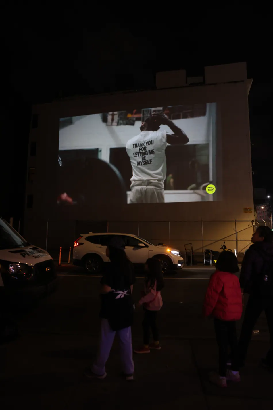 Crowd watching a projected campaign on a city wall